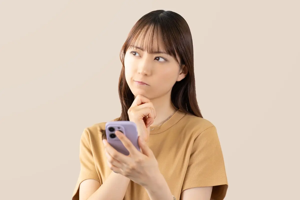 スマホをもって悩んでいる女性