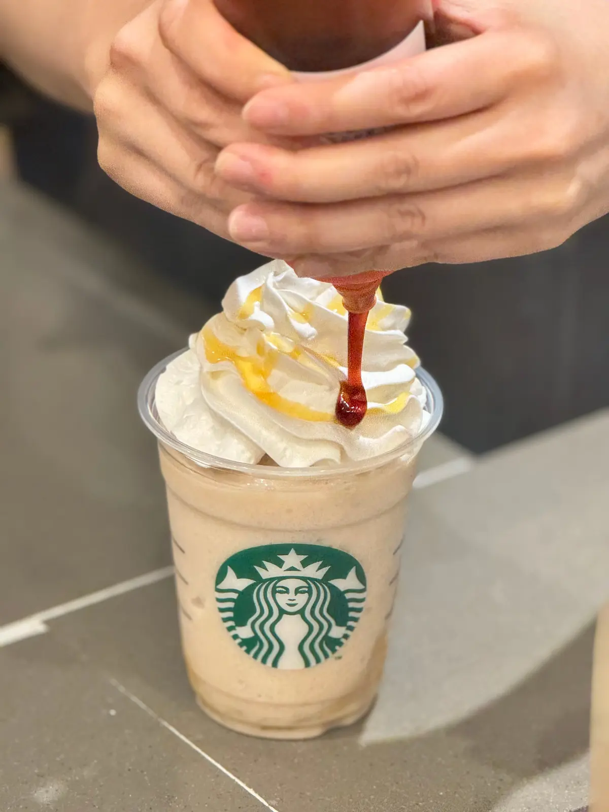 ホットソースをトッピングしているスタバ店員の手元