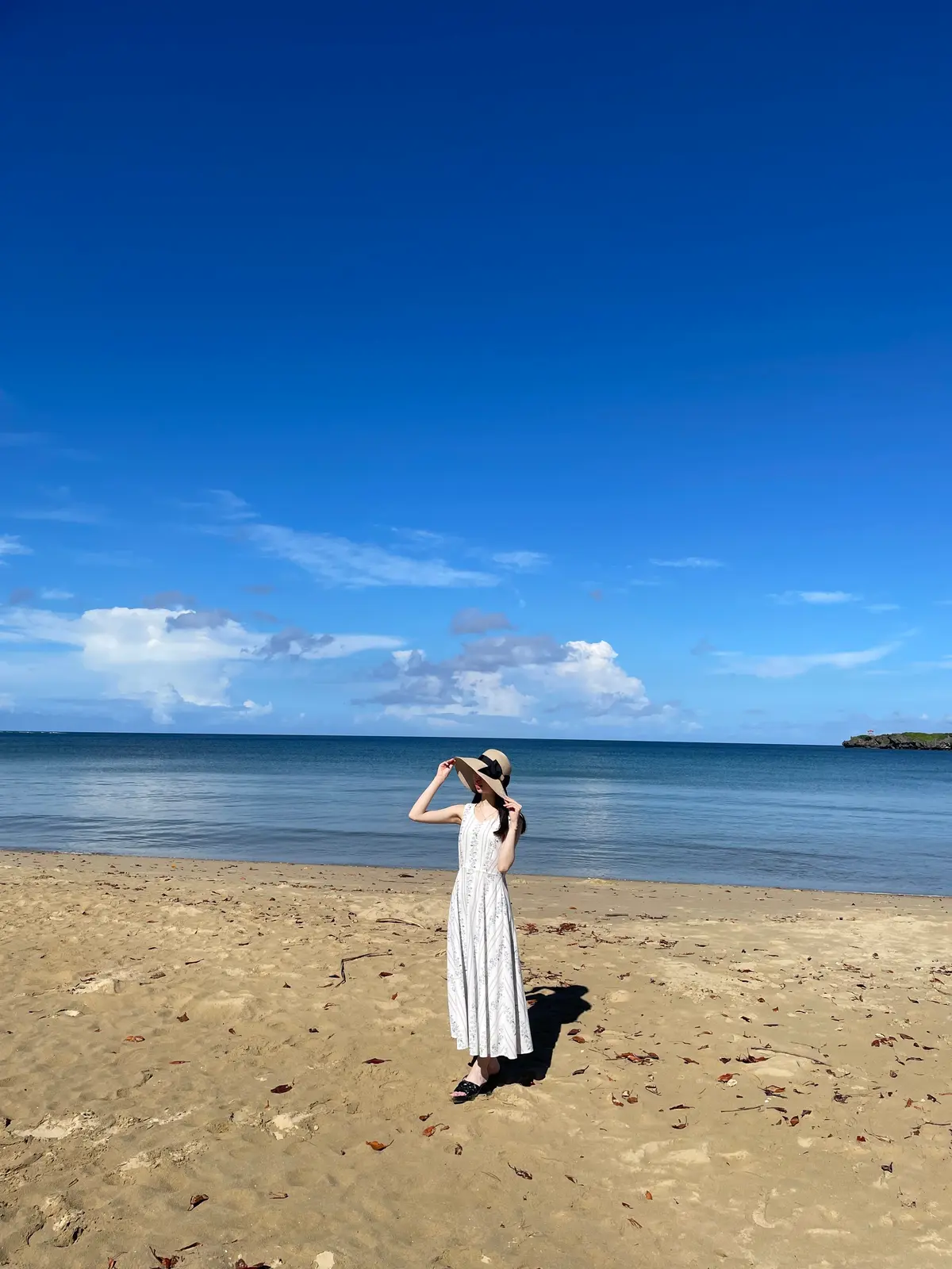 麦わら帽子を被ってロングワンピースを着て海にいる藤田雅馨(ふじたみやか)