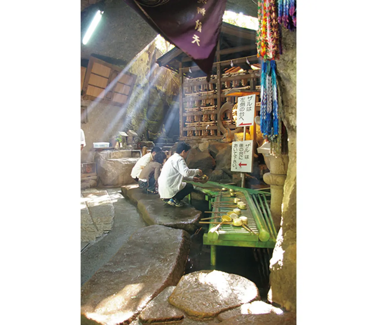 銭洗弁財天 宇賀福神社 岩窟内でお金を洗う人