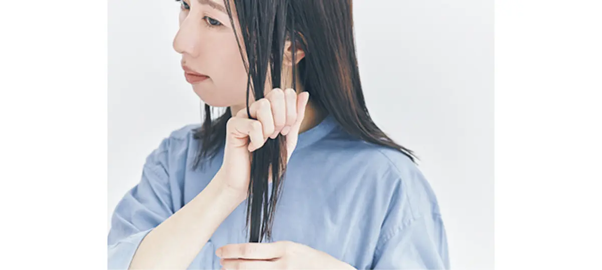 ヘアオイルを髪につける女性