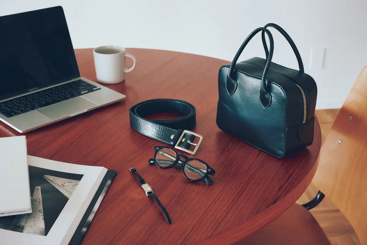 テーブルに置かれた黒バッグ、メガネ、ベルト、腕時計