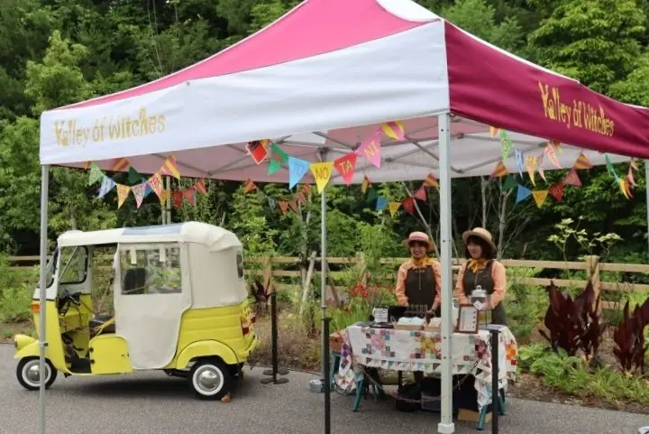 『ジブリパーク』「魔女の谷」の「オキノ邸」前に、晴れの日限定で出現するお便り茶販売テント＆ワゴン