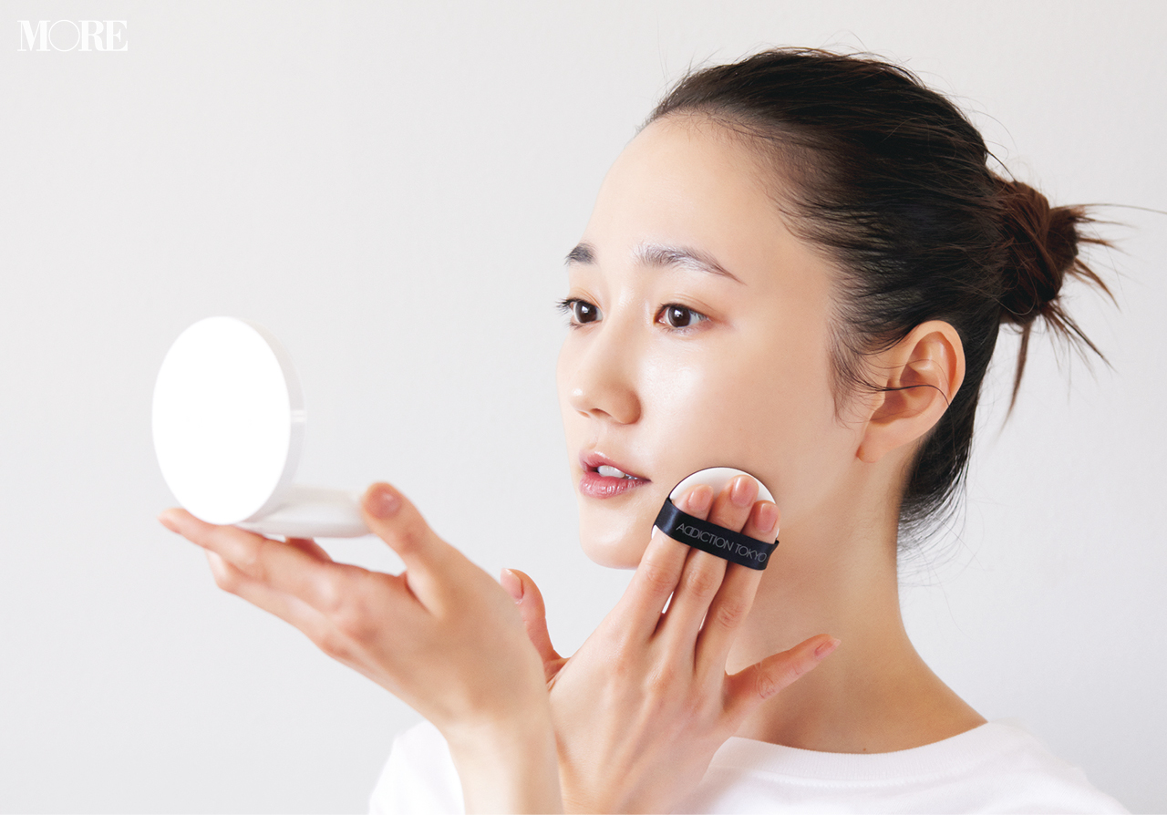 化粧下地を顔に塗る女性